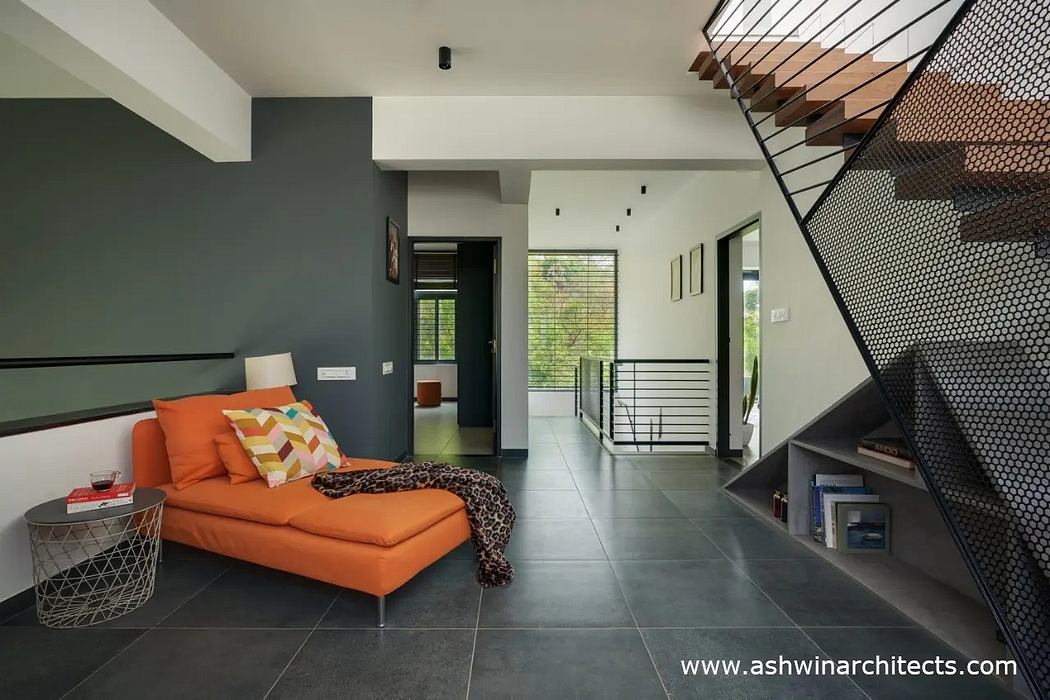Sleek, modern interior with bold orange sofa, metal railings, and geometric floor tiles.