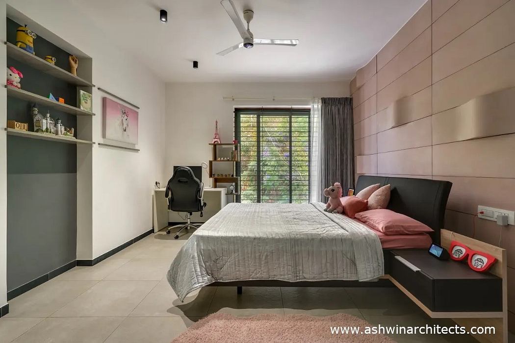 Cozy bedroom with modern furnishings, built-in shelving, and large windows overlooking greenery.