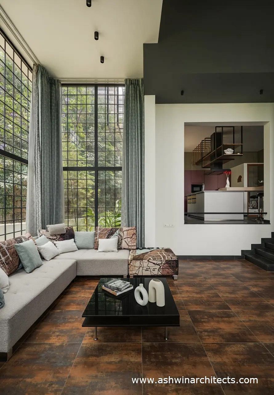 Spacious living room with large windows, modern furniture, and sleek kitchen design.