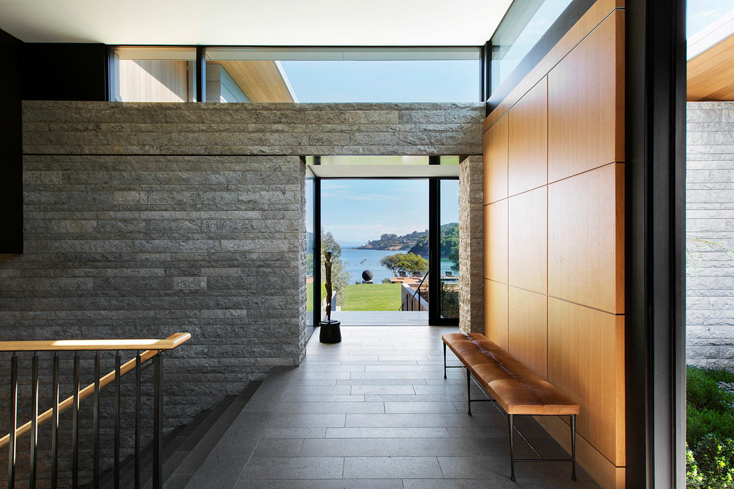 Minimalist interior with stone walls, wooden furnishings, and a scenic outdoor view.