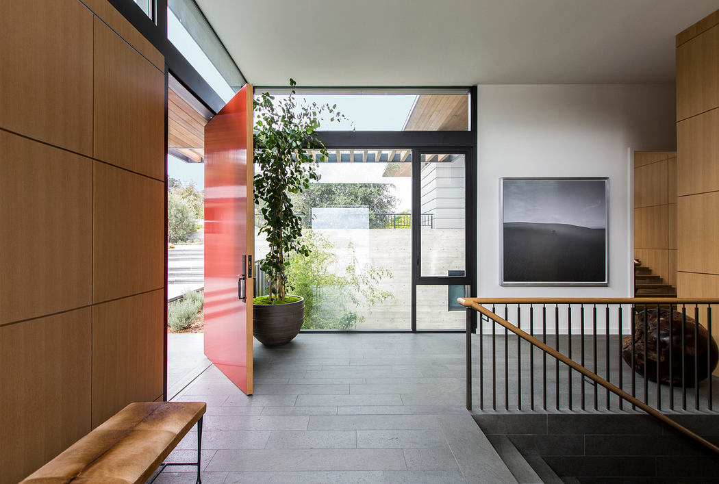 Modern entryway with sleek wood panels, glass doors, and a potted plant providing a touch of nature.