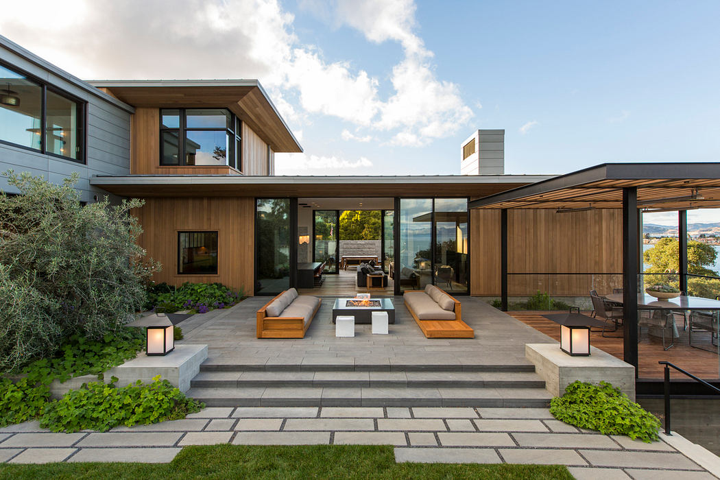 Sleek modern home with wood accents, large windows, and a cozy outdoor patio area.