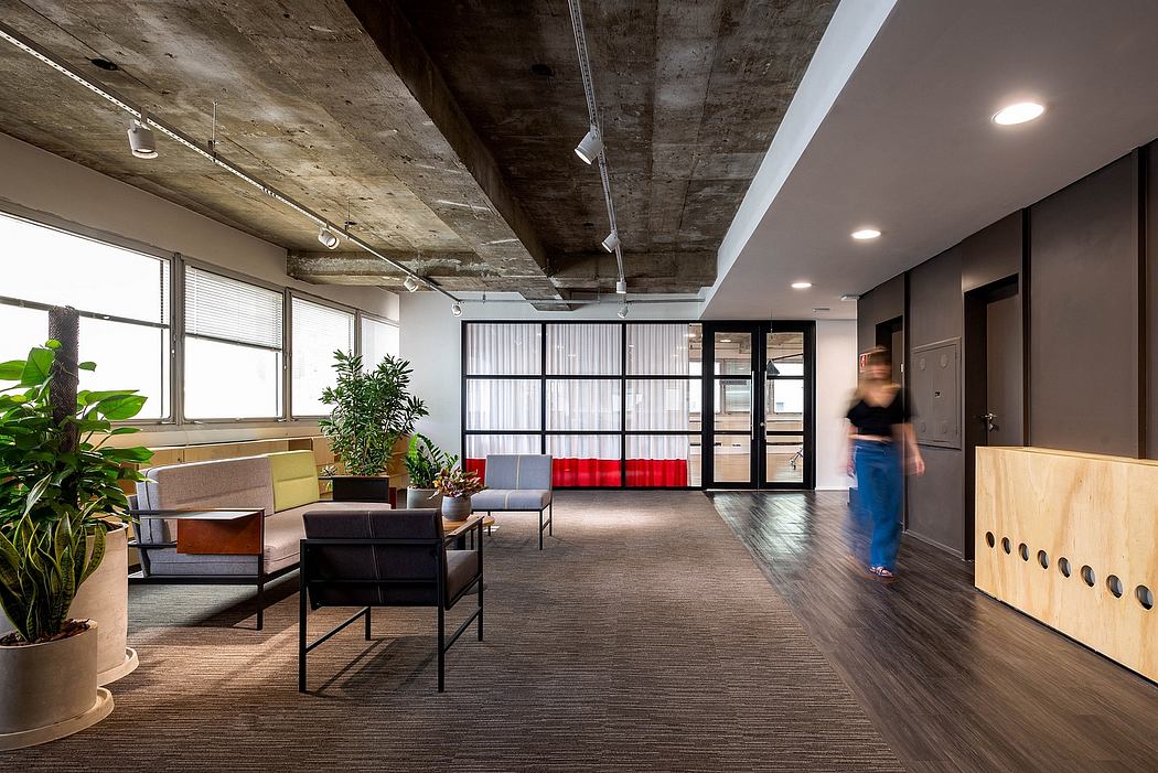 A contemporary office space with exposed concrete ceiling, plants, and modern furniture.