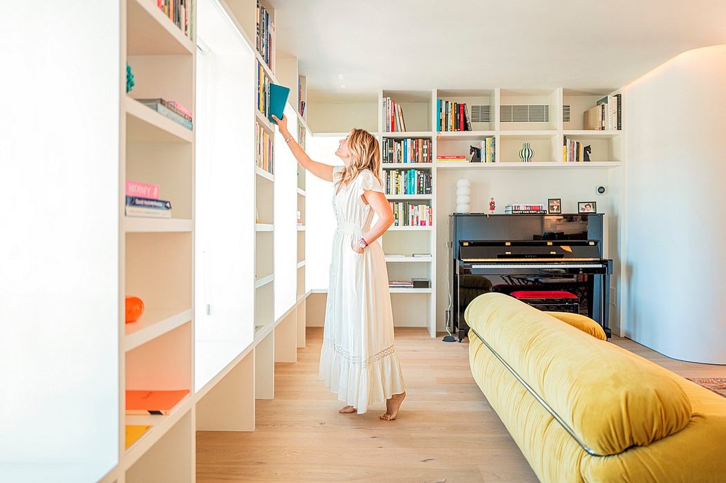 Airy, minimalistic living room with built-in bookshelves, piano, and yellow sofa.