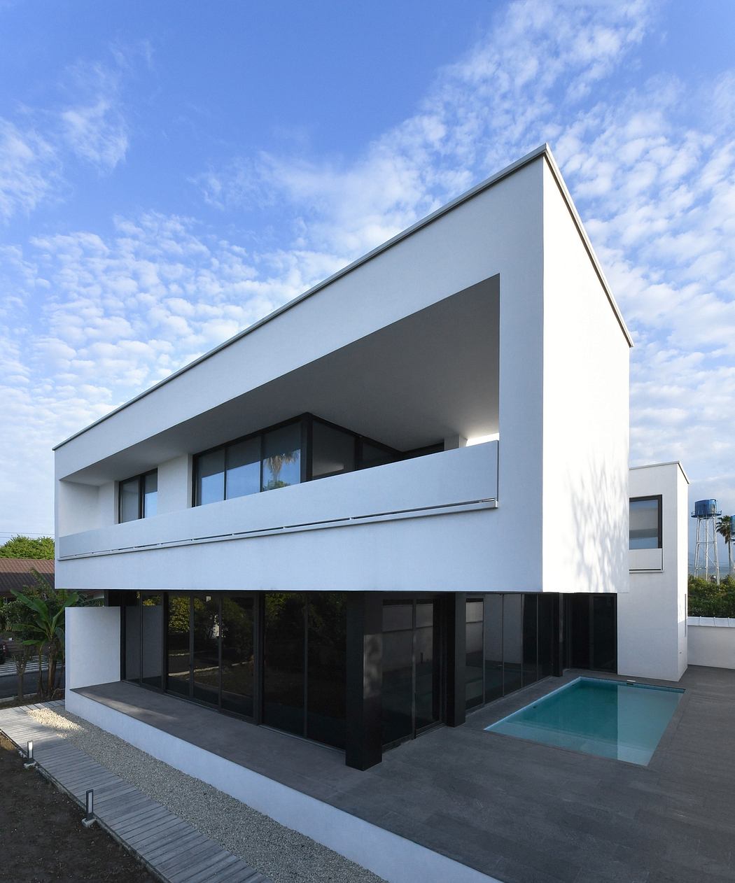 A sleek, modern two-story home with large windows and a rectangular pool.