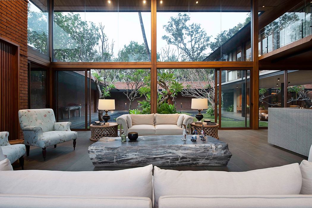 Expansive glass walls frame a lush outdoor oasis, accented by a striking marble coffee table.