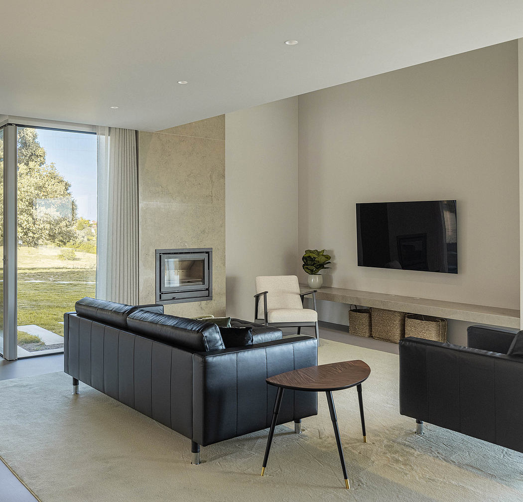 Modern living room with sleek leather sofa, stone fireplace, and large window overlooking outdoor scenery.