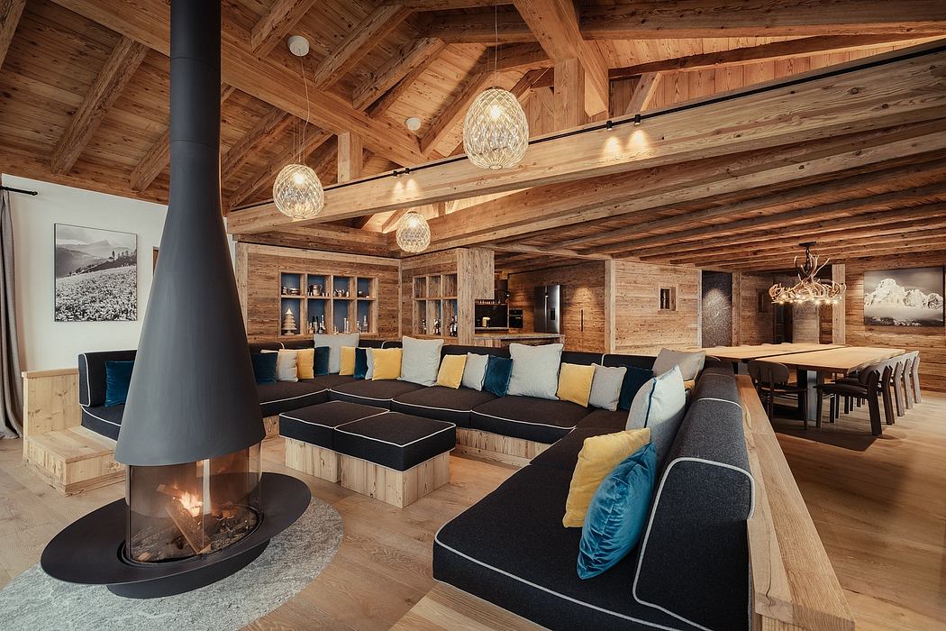 Cozy, rustic interior with wooden beams, pendant lights, and a central fireplace.