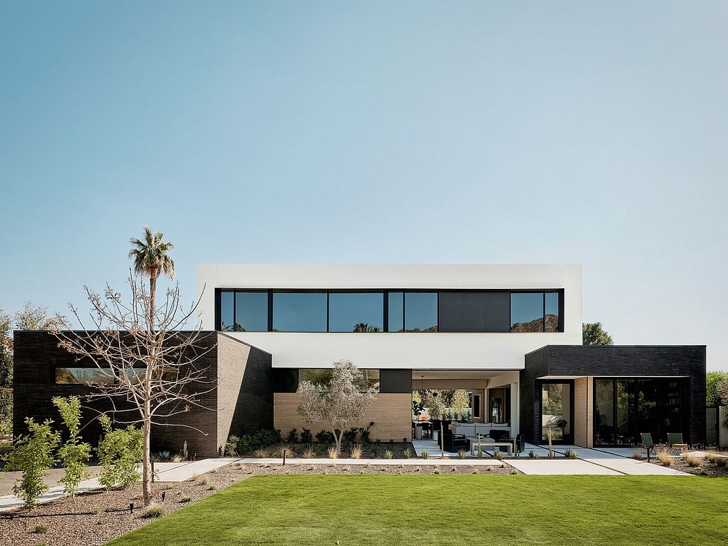 A modern, minimalist home with sleek glass and concrete facade, surrounded by lush greenery.