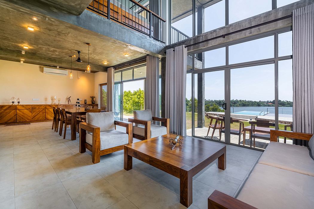 Modern open-plan living space with concrete ceilings, wooden furniture, and floor-to-ceiling windows overlooking a pool and lush greenery.