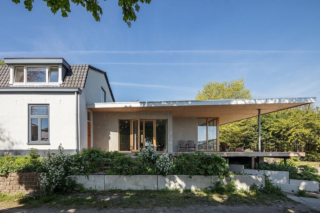 A modern house with a large covered patio, extensive landscaping, and natural materials.