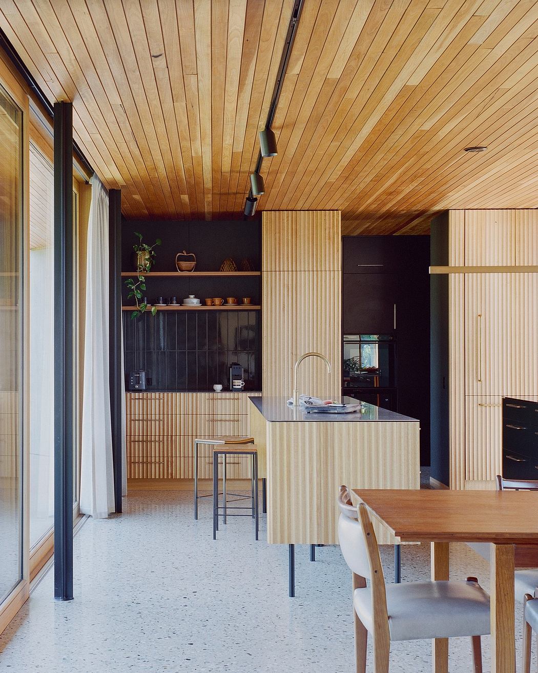 Warm wooden ceiling and cabinetry, contrasting dark accent walls, minimalist kitchen.