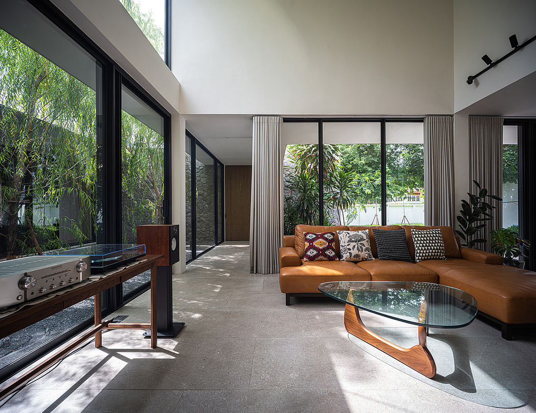 Spacious modern living room with large windows overlooking lush greenery outside.