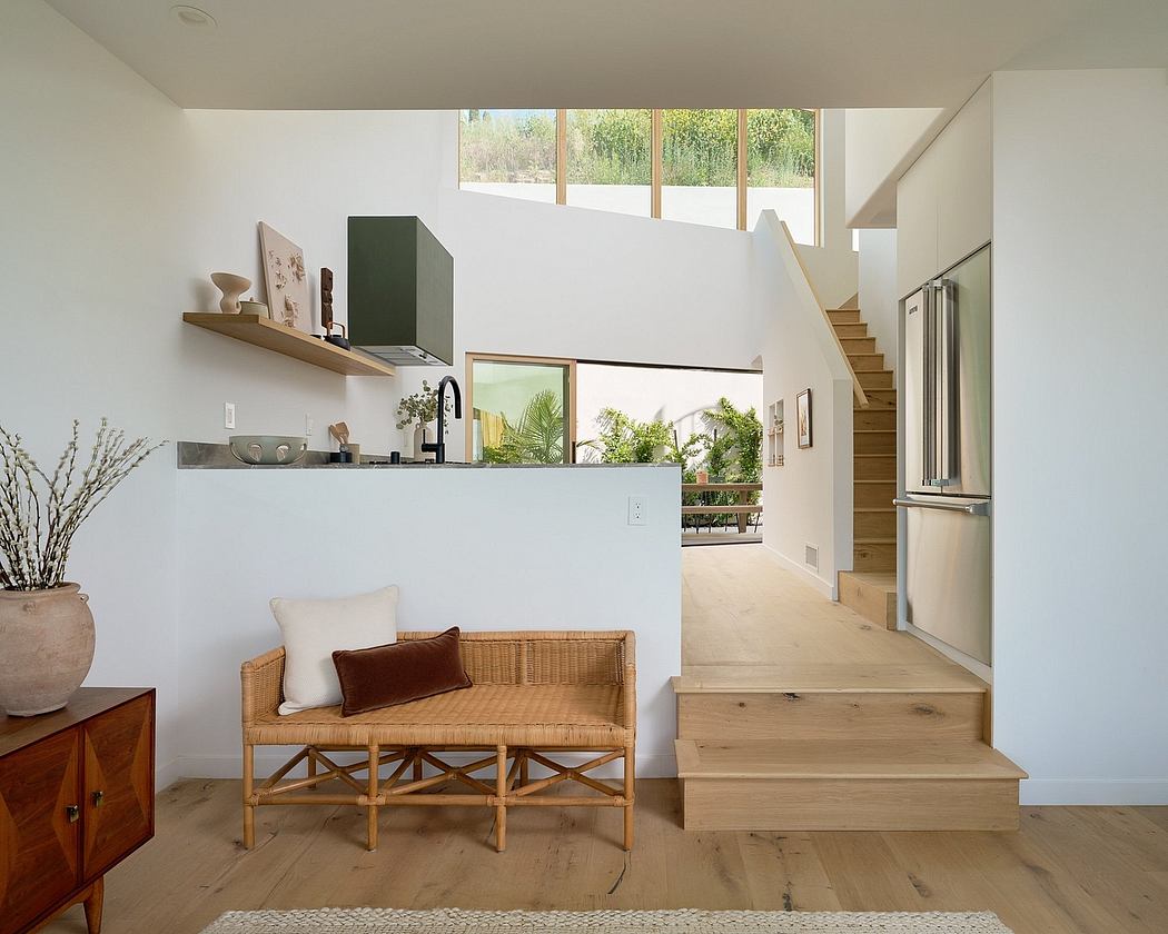 Bright, open-plan interior with wooden furniture, stairs, and views of the outdoors.