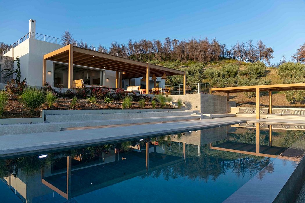 Modern outdoor terrace with covered seating area, reflecting pool, and lush landscaping.