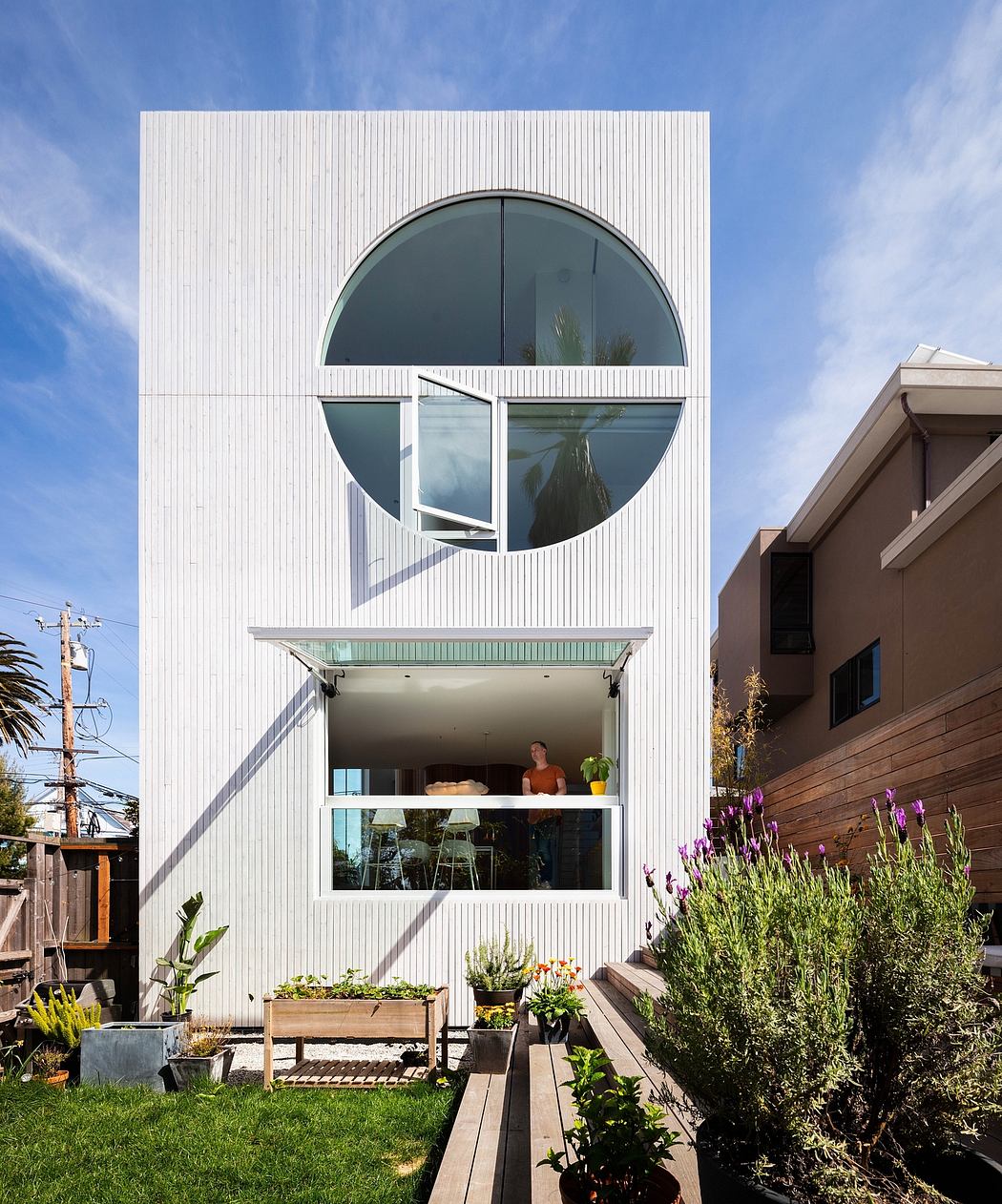 Striking modern architecture with circular glass window, covered patio, and lush greenery.