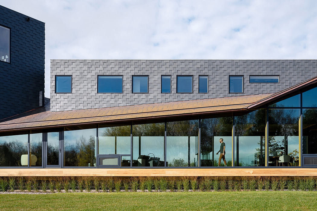 A modern building with large windows, a wooden roof, and a well-landscaped exterior.