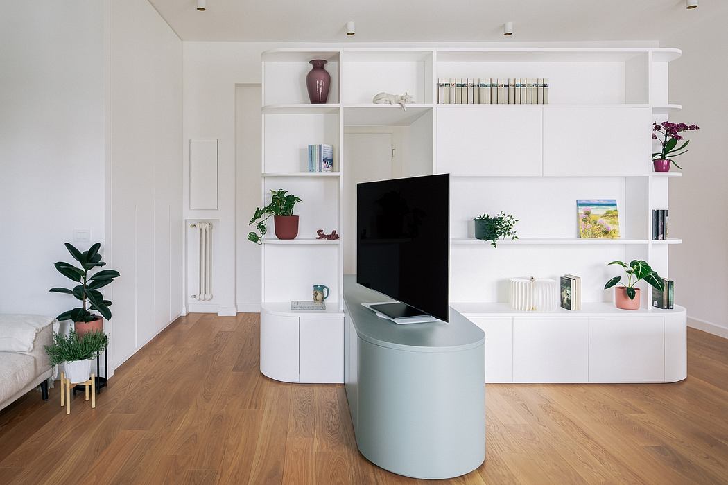 Modern, minimalist living room with white built-in shelving, TV console, and wood floor.