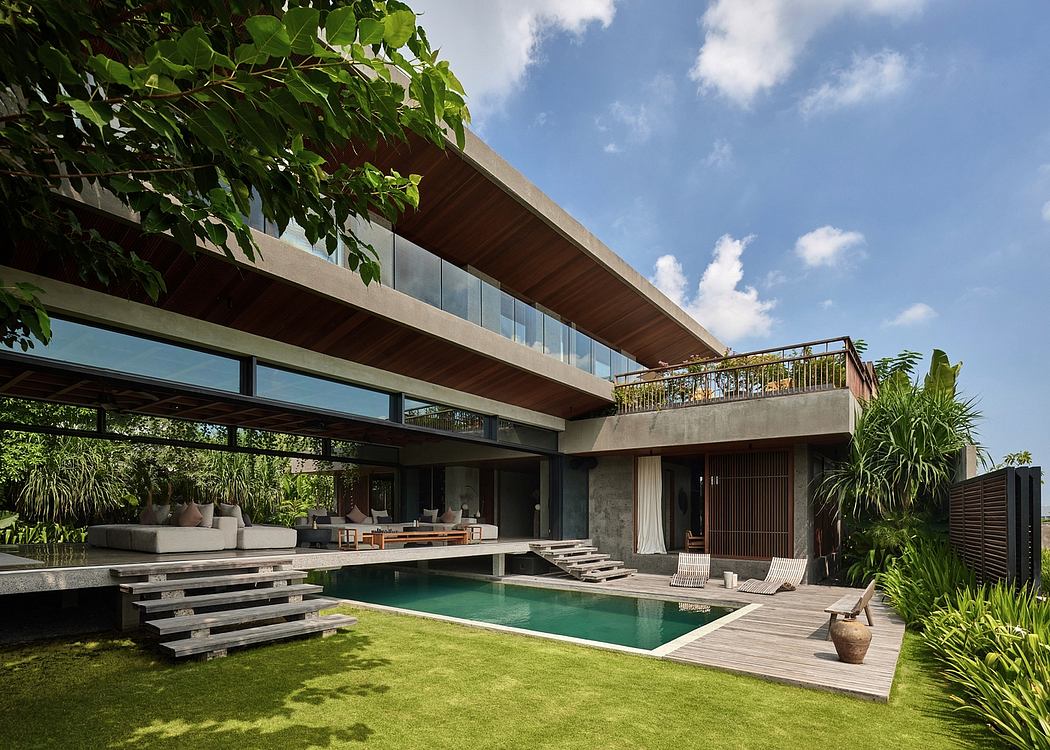 Expansive contemporary tropical villa with elevated timber overhang, pool, and lush landscaping.