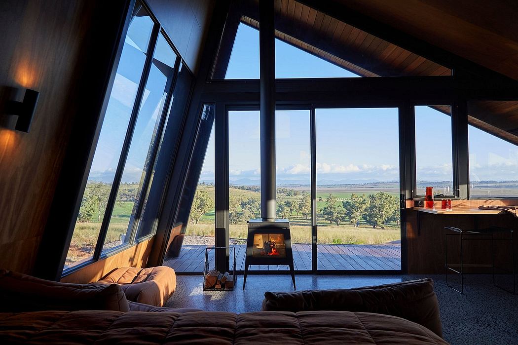 Cozy cabin interior with large floor-to-ceiling windows offering stunning countryside views.
