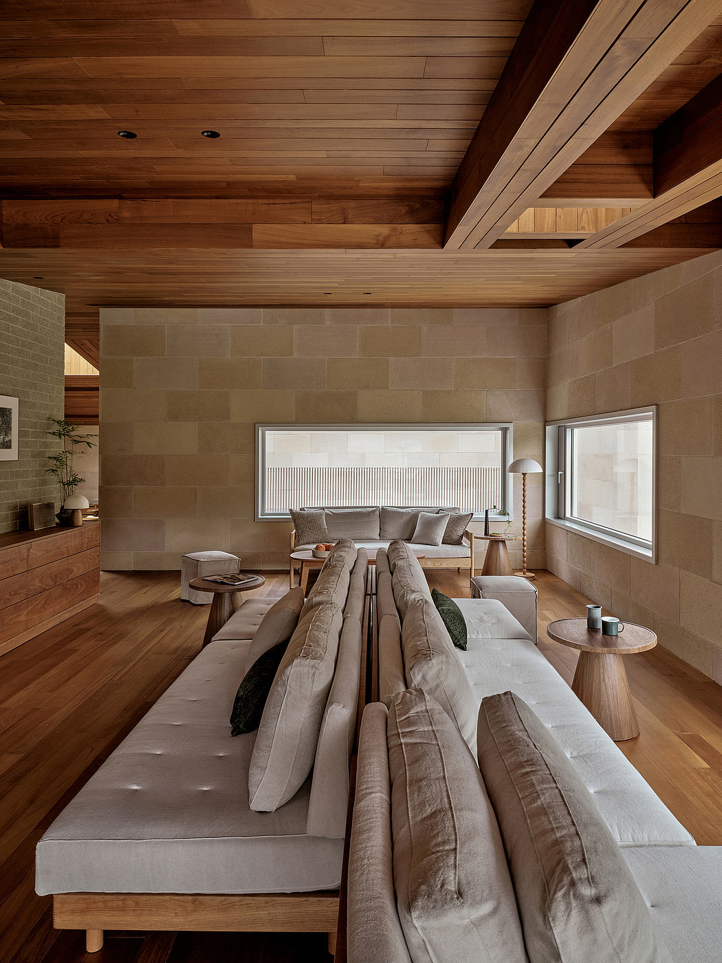 Warm, modern living space with wood beamed ceiling, stone walls, and plush seating.