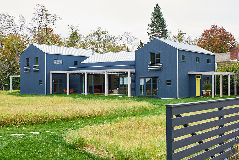 Sleek, modern farmhouse with a mix of blue and yellow accents against a lush landscape.