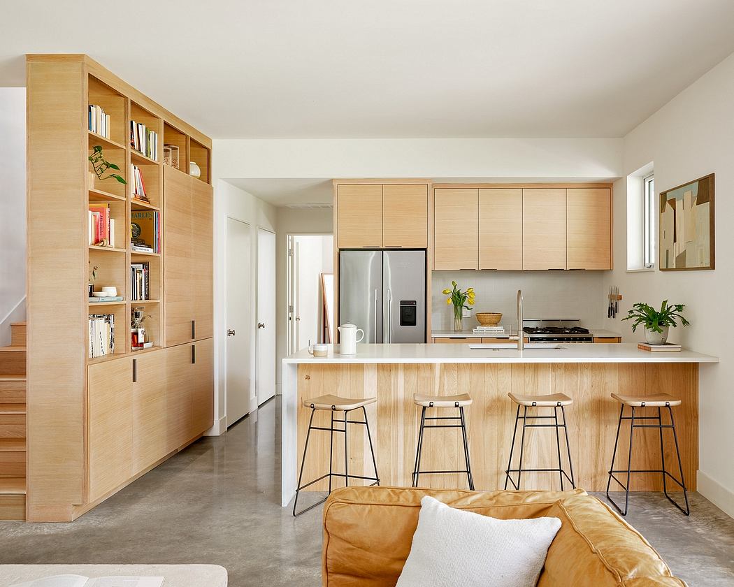 Minimalist open-concept kitchen with wooden cabinetry, concrete floors, and bar seating.