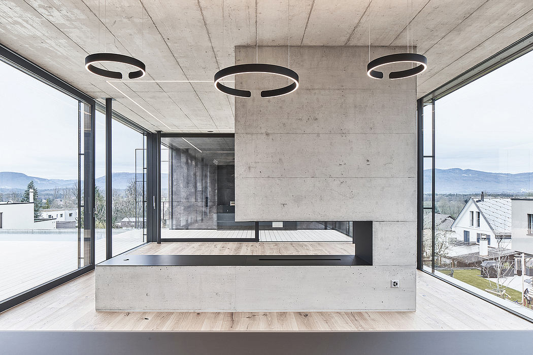 Modern concrete interior with circular pendant lights, expansive windows, and a raised platform.