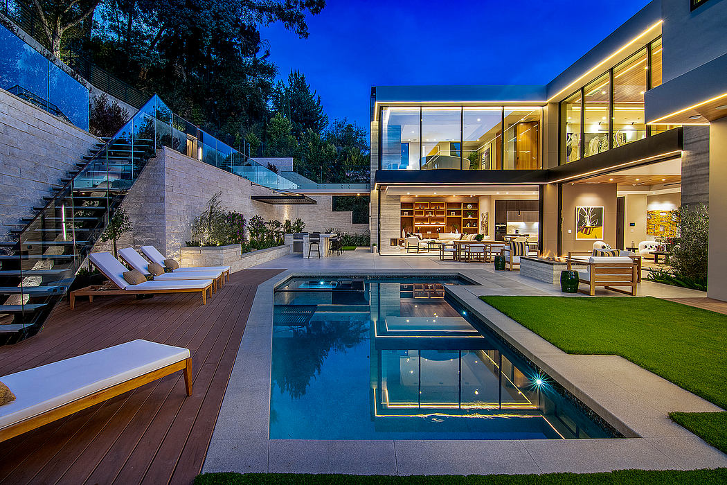 Stunning modern home with pool, deck, and outdoor living area at night.