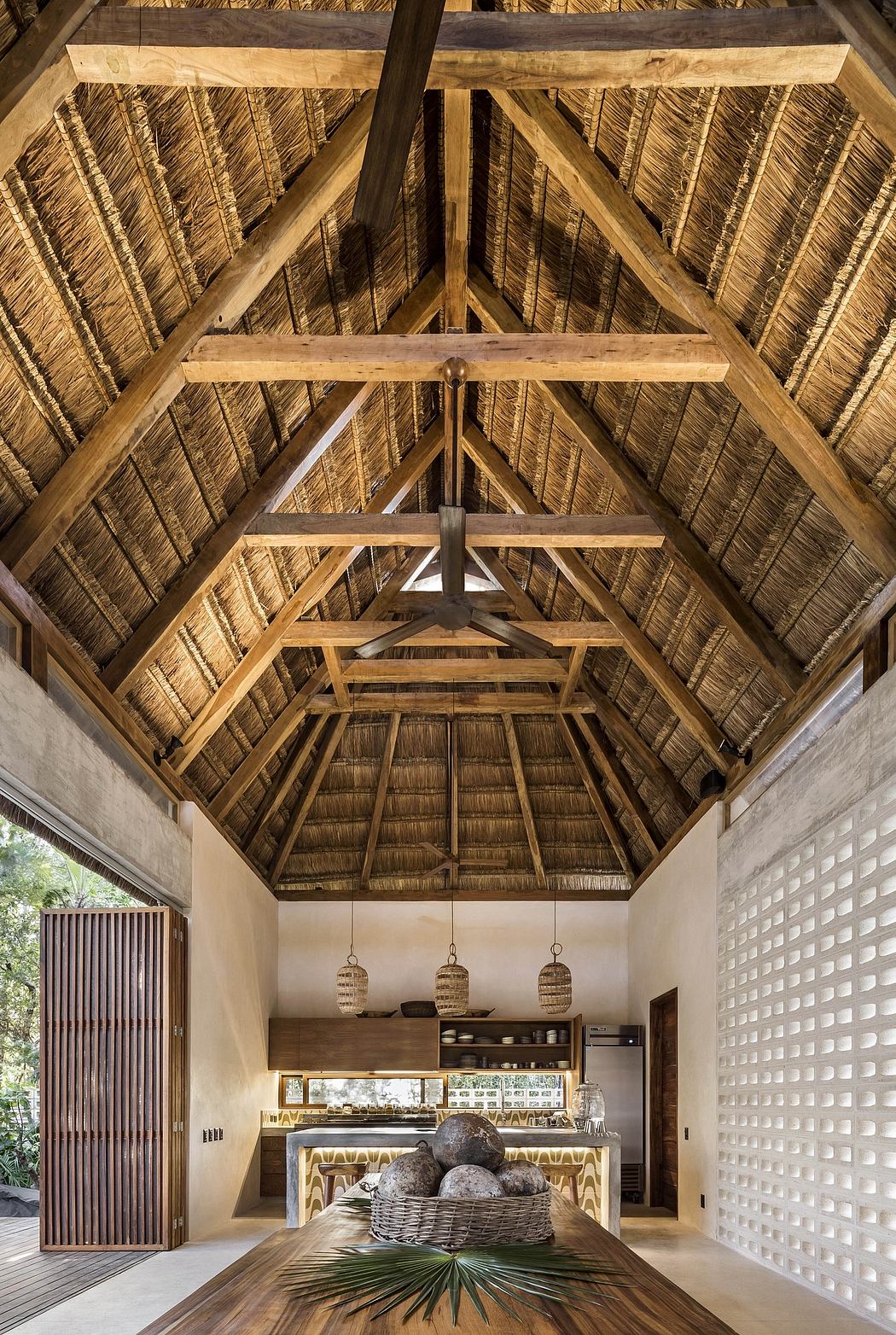 An ornate wooden roof structure with intricate bamboo paneling and pendant lighting in a rustic kitchen interior.