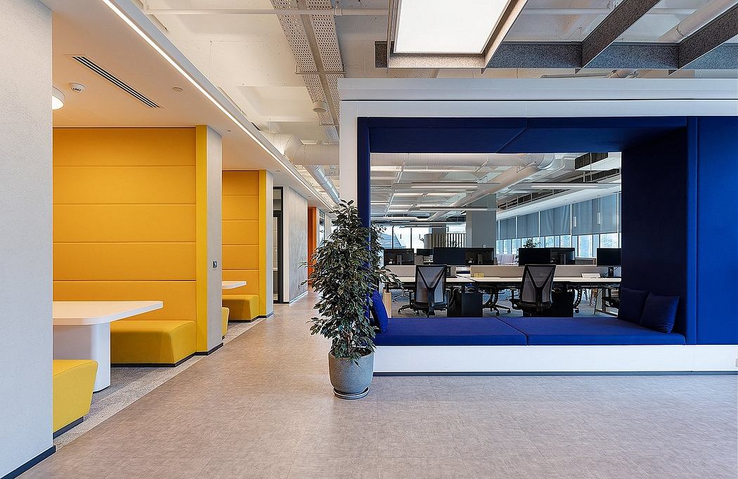 A modern office space with vibrant yellow and blue color scheme, featuring an open layout and natural lighting.