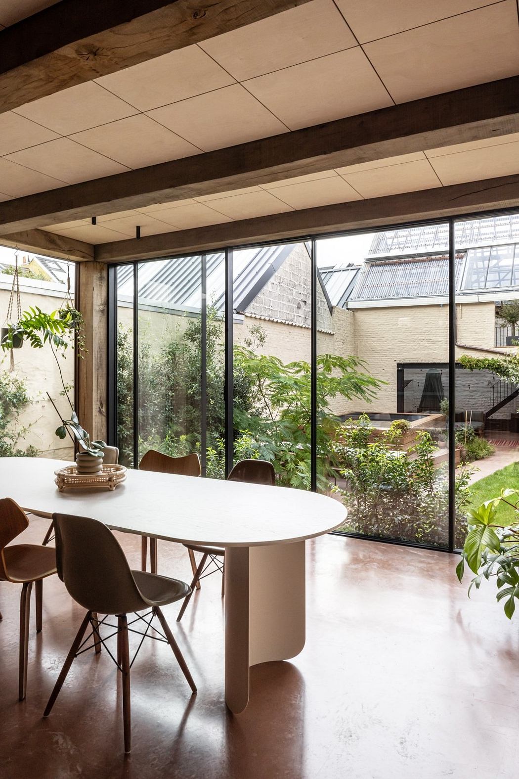 A modern, open-concept dining area with expansive windows overlooking a lush garden.
