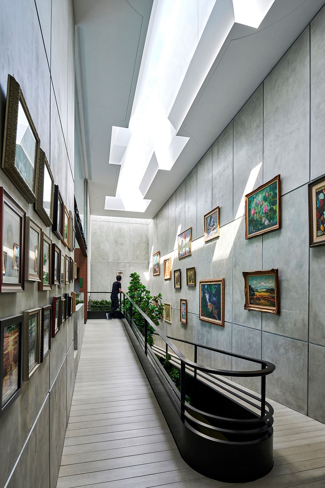 A contemporary art gallery with a minimalist design, featuring suspended lighting, artwork-lined walls, and a curved bench.