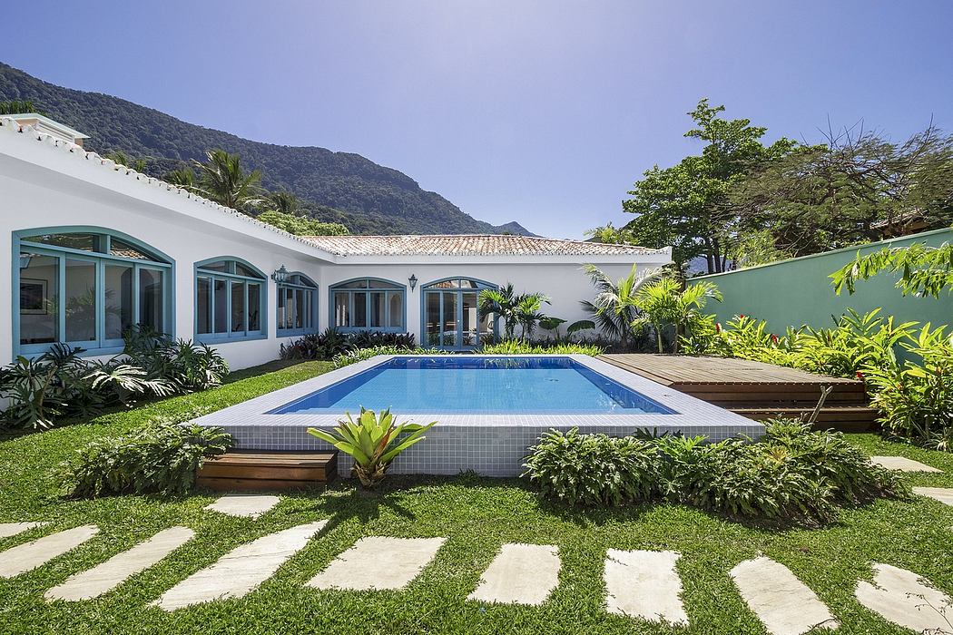 Elegant white villa with arched windows, lush greenery, and a sparkling pool.