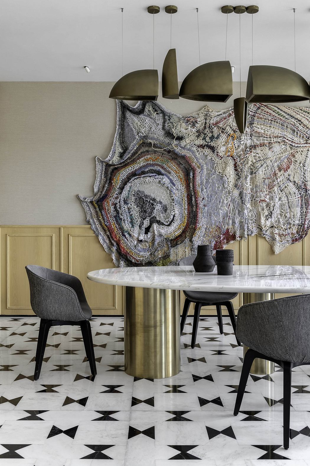 Striking geometric tile flooring, plush upholstered chairs, and an ornate textile artwork.