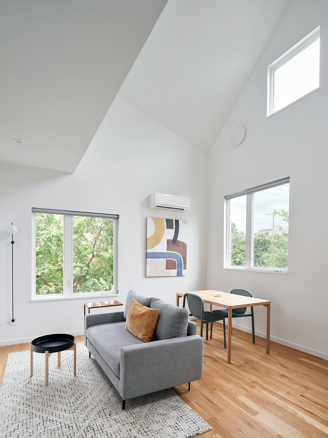 Bright, minimal living room with vaulted ceiling, wood floors, and modern furnishings.