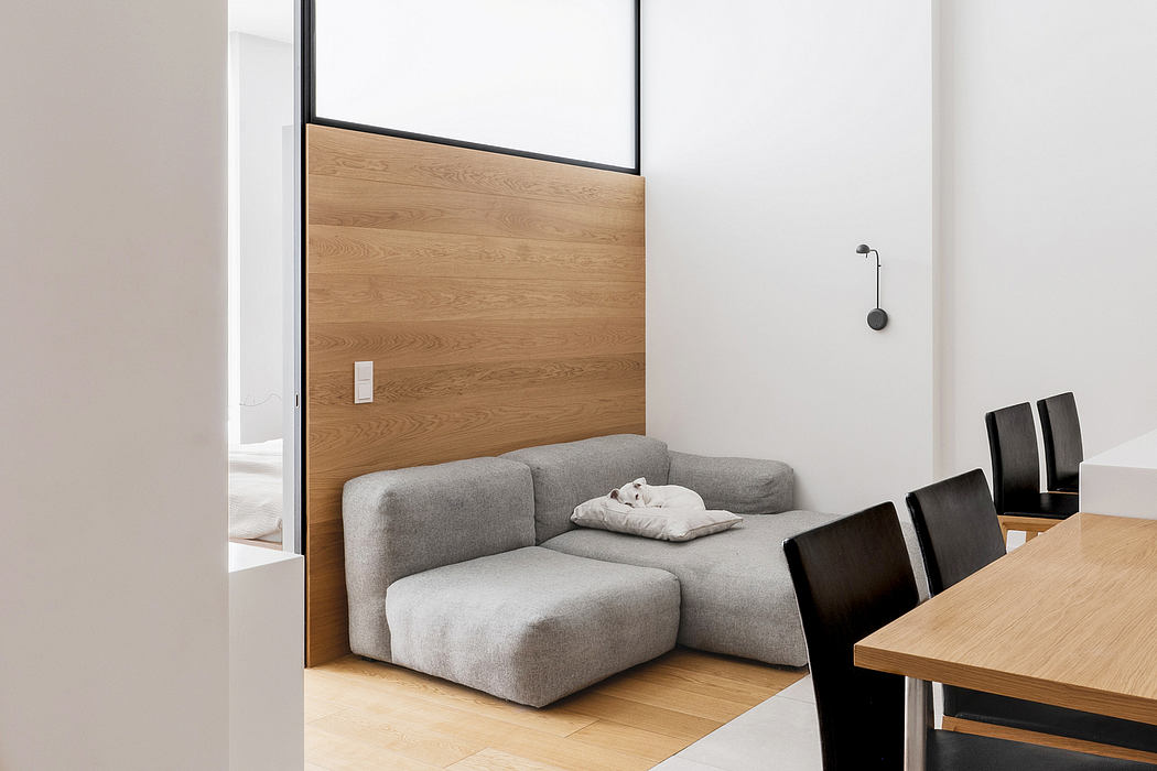 Minimalist living space with wooden accent wall, gray sofa, and simple furnishings.