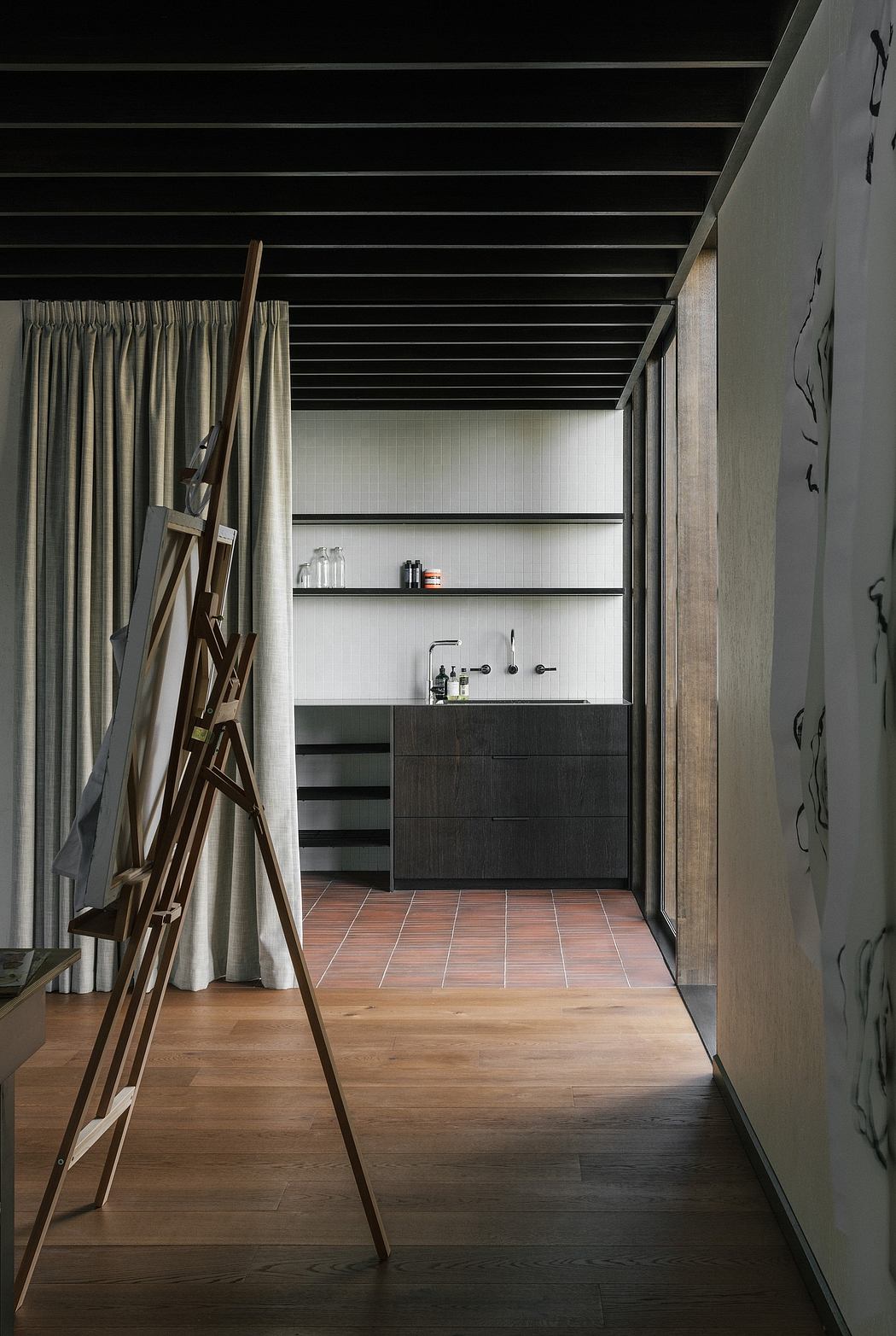 Minimal, wood-paneled room with wooden easel and industrial-style drawers.