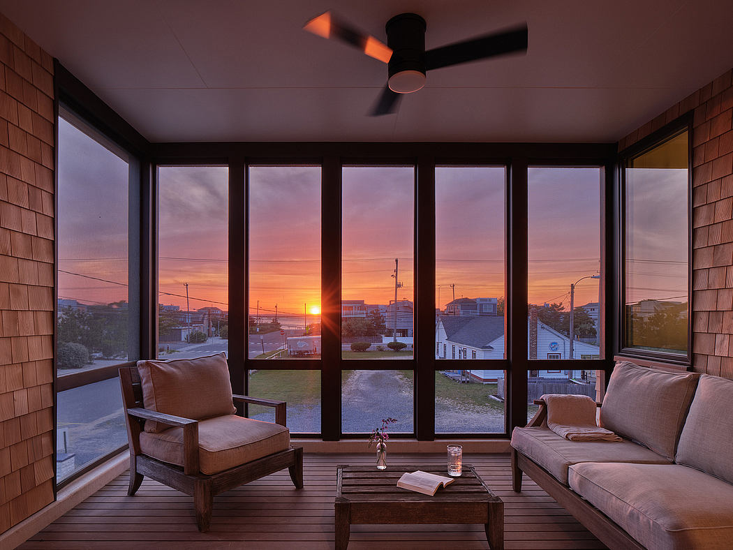 A cozy living room with large windows showcasing a stunning sunset over a cityscape.