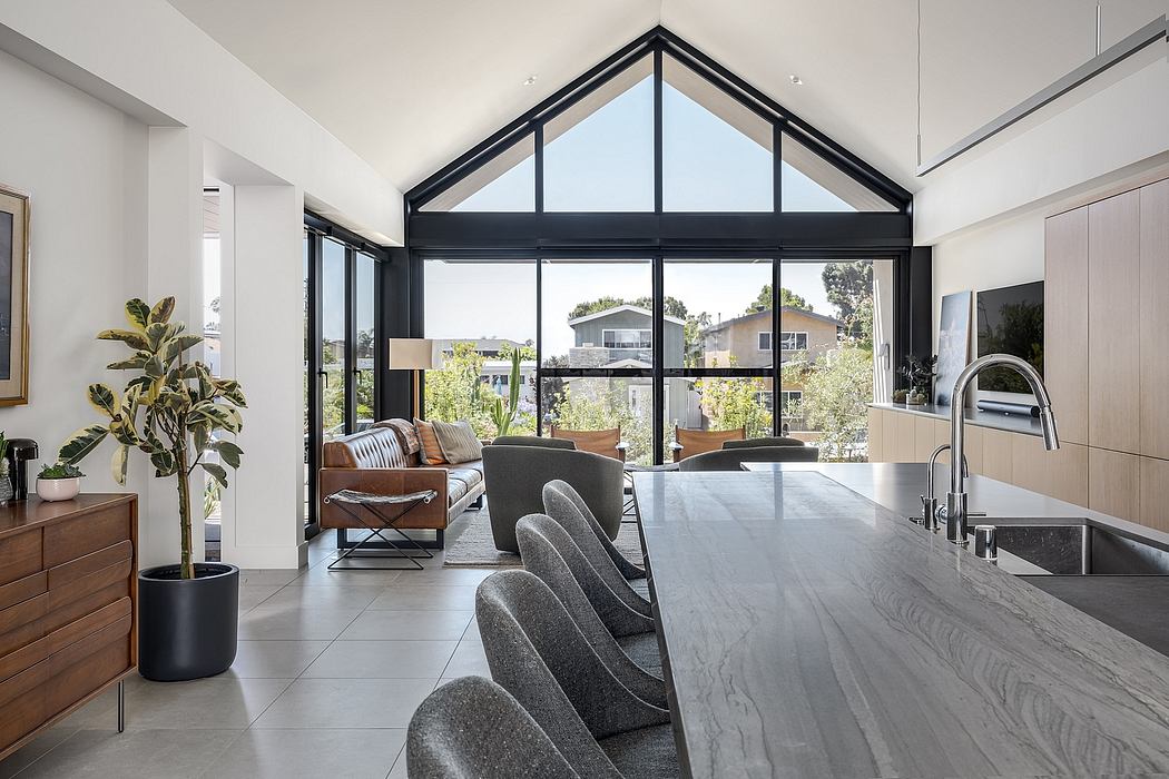 Bright, modern open-plan living space with vaulted ceiling, large windows, and sleek furnishings.