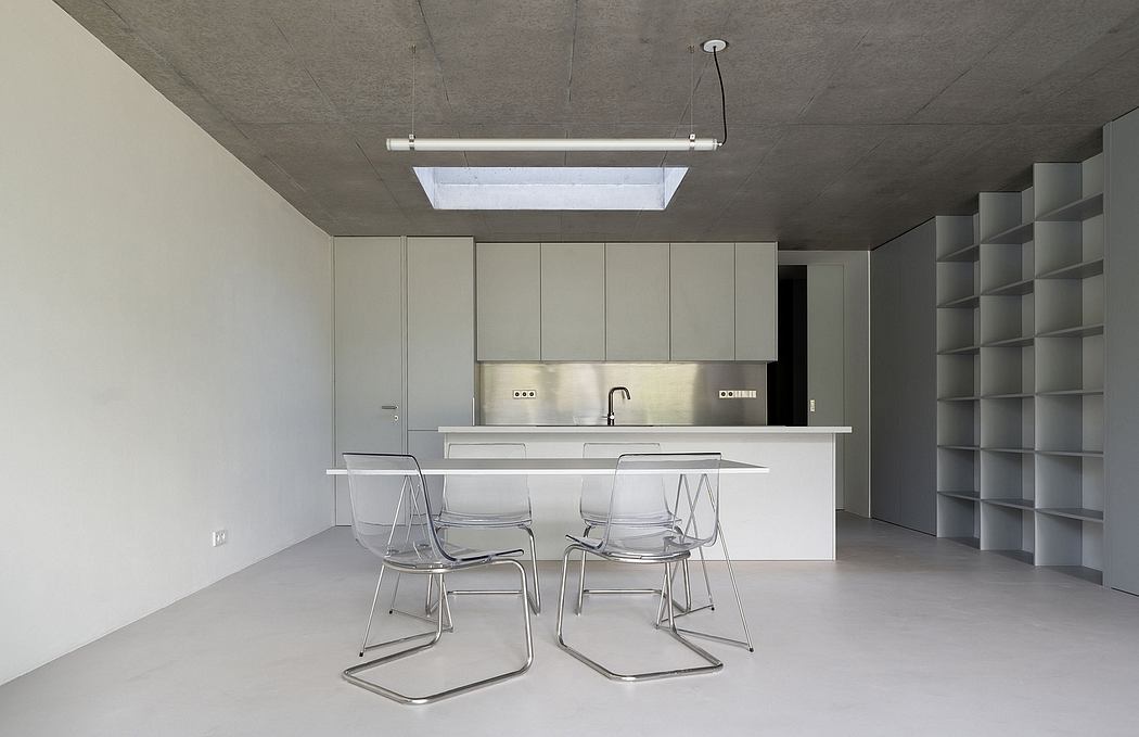 Modern, minimalist kitchen with clean lines, concrete ceiling, and transparent chairs.