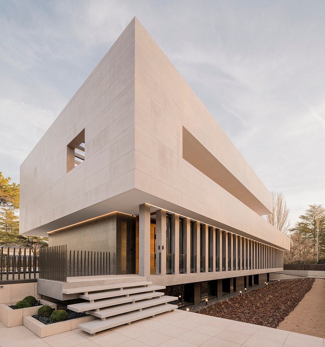 Modern, rectangular building with uniform facade and glass panels, surrounded by landscaping.