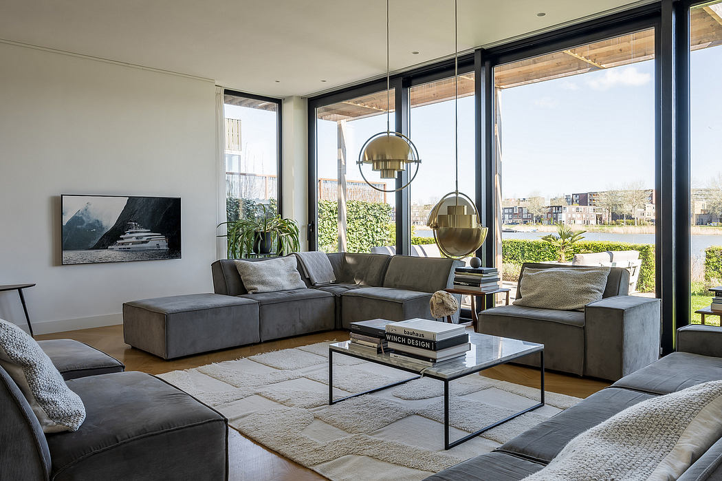 Spacious modern living room with large windows, plush gray sofas, and elegant pendant lights.