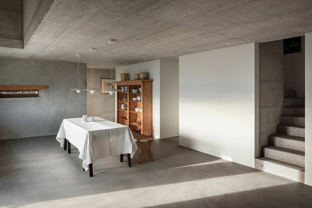 Minimalist interior with concrete ceilings, rustic wooden accents, and a simple dining table setup.