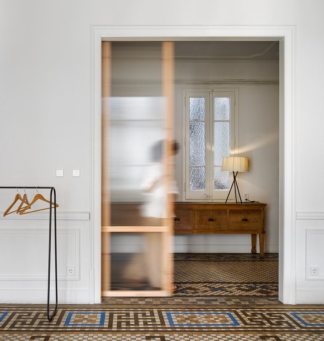 A bright, modern entryway with Art Deco-inspired floor tiles, antique furniture, and a lamp.