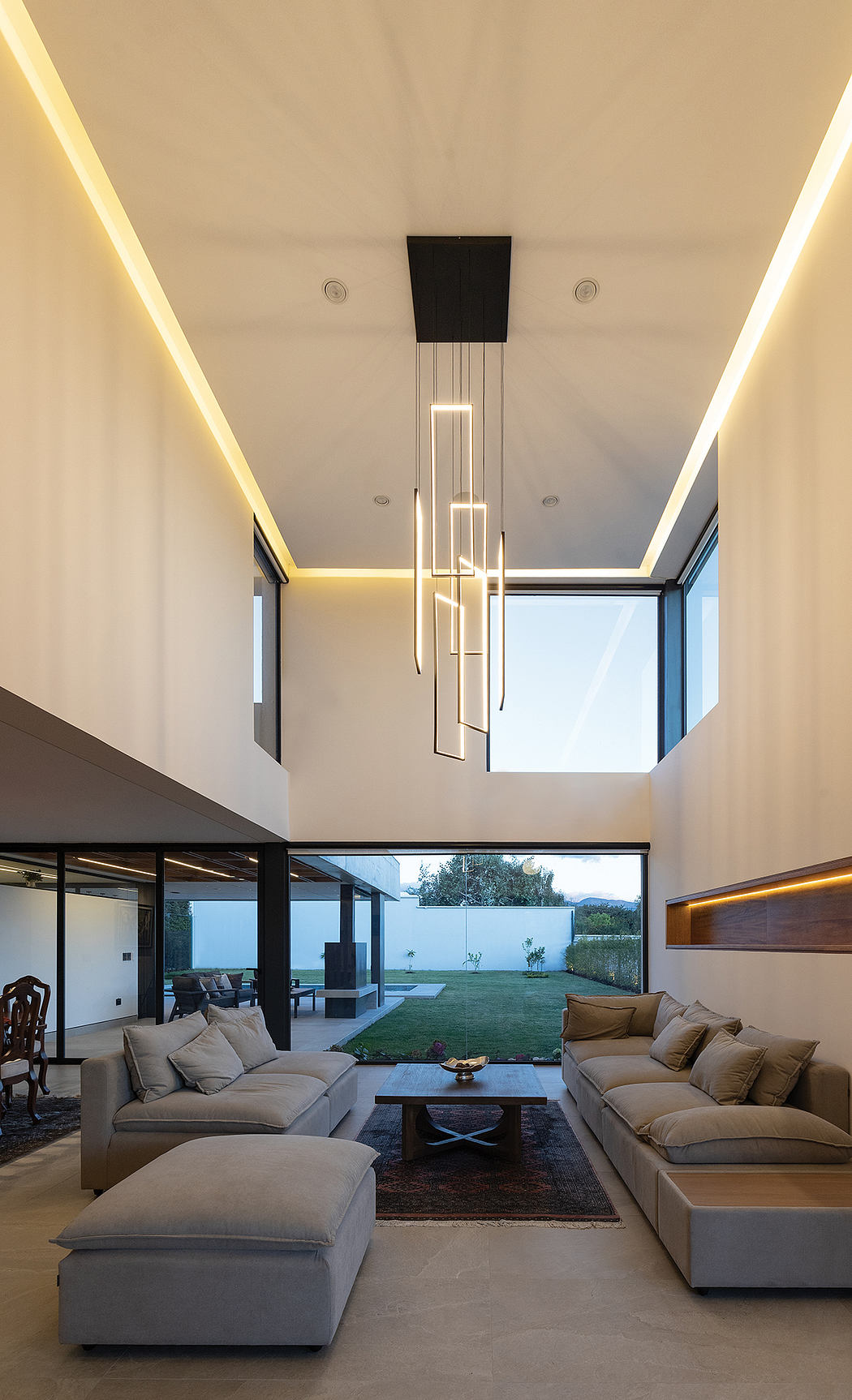 Modern living room with sleek lighting fixtures, large windows, and a cozy outdoor view.