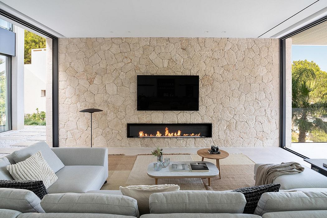 Modern living room with stone feature wall, fireplace, and floor-to-ceiling windows offering outdoor views.