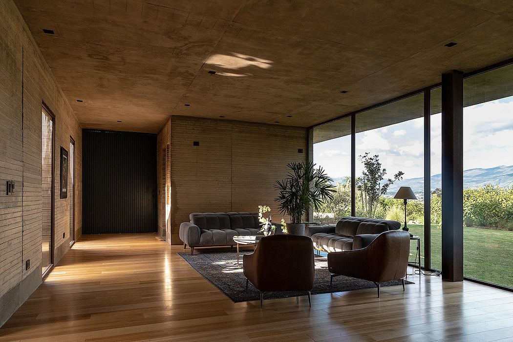 A spacious living room with concrete walls, hardwood floors, and large windows overlooking the landscape.
