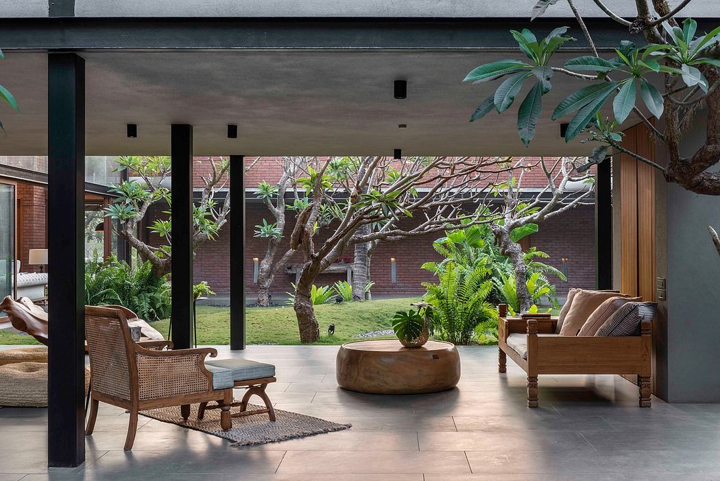 Elegant indoor-outdoor living space with lush tropical plants, modern furniture, and large glass windows.