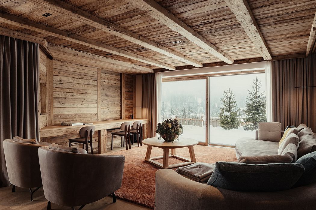 Cozy rustic cabin interior with wooden beams, plush furniture, and snowy mountain view.